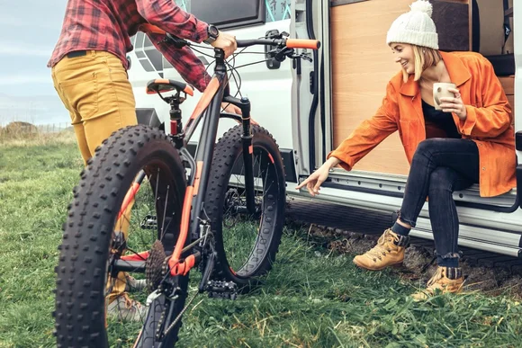 Zwei Personen mit Fahrrad an einem Wohnmobil